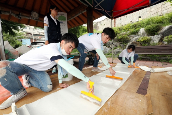 지난 13일 대우건설 대학생 홍보대사들이 서울시 성북구에 위치한 노후주택에 도배할 벽지에 풀을 바르고 있다. (사진=대우건설 제공)